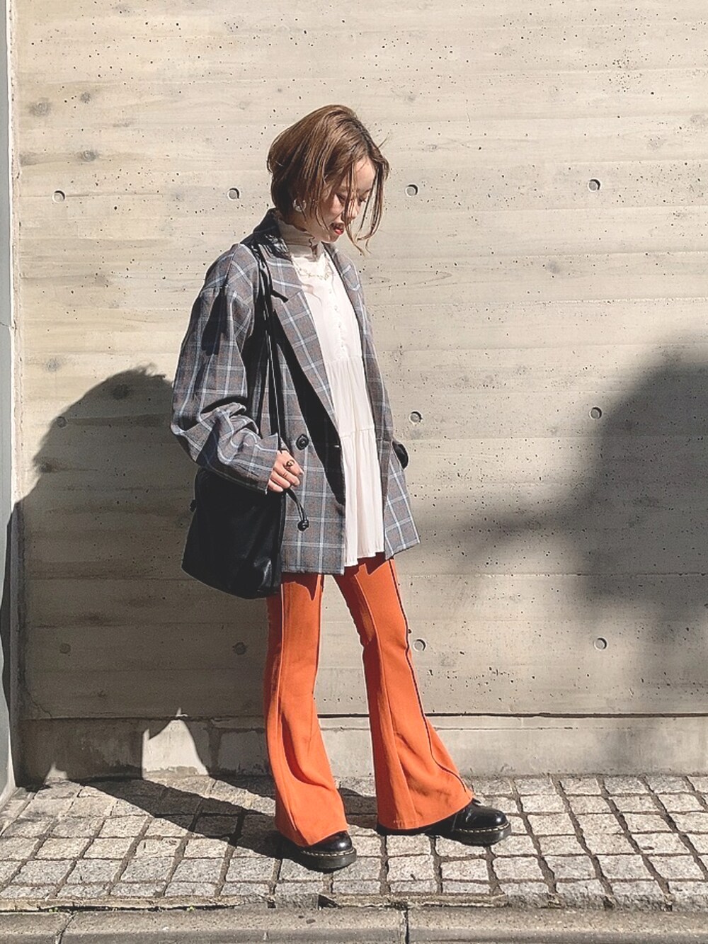 オレンジ系のパンツ、ブラック系のシューズ、ホワイト系のシャツ/ブラウスを着用したレディースの秋コーディネートの2枚目の写真