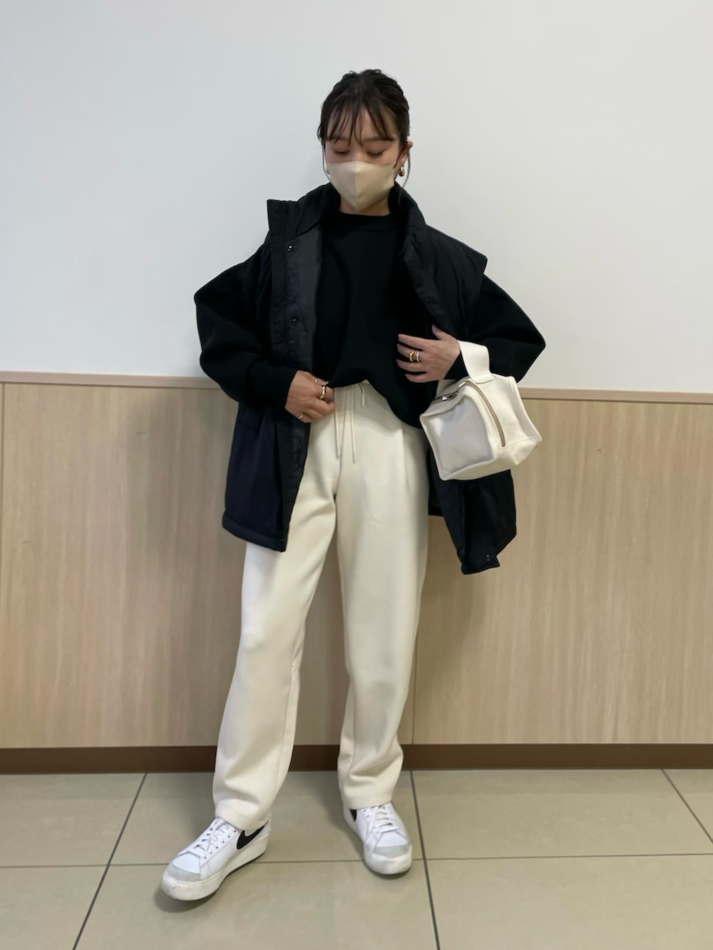 ブラック系のニット/セーター、ホワイト系のスニーカー、ブラック系のダウンベストを着用したレディースの秋コーディネートの2枚目の写真