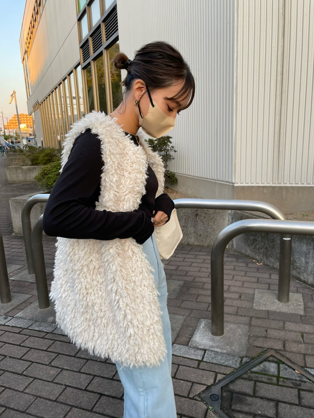 ホワイト系のベスト、ブルー系のデニムパンツを着用したレディースの秋コーディネートの2枚目の写真