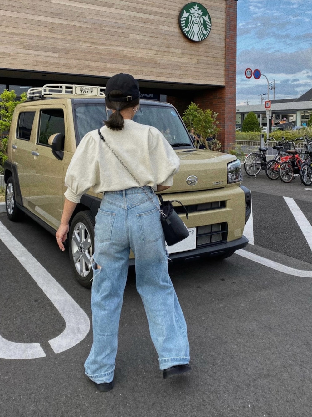 ホワイト系のTシャツ/カットソー、ブルー系のデニムパンツ、ブラック系のバッグを着用したレディースの春コーディネートの2枚目の写真
