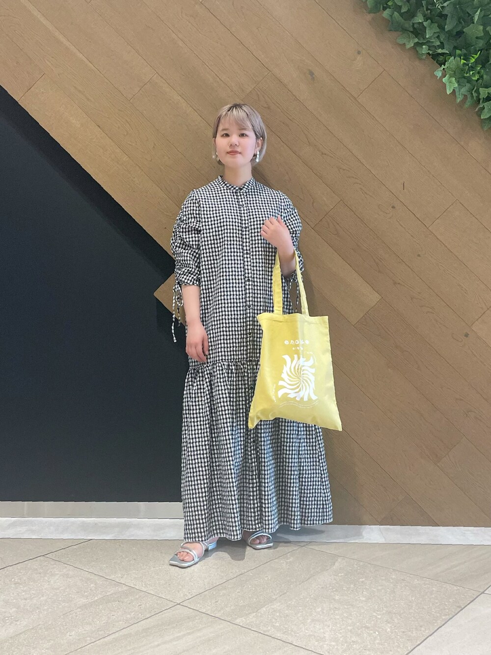 ブラック系のワンピース、イエロー系のトートバッグ、シルバー系のサンダルを着用したレディースの春コーディネートの3枚目の写真