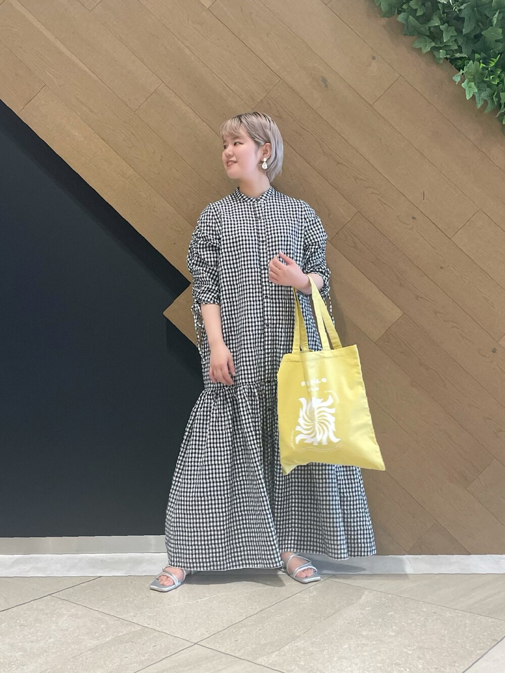ブラック系のワンピース、イエロー系のトートバッグ、シルバー系のサンダルを着用したレディースの春コーディネートの2枚目の写真