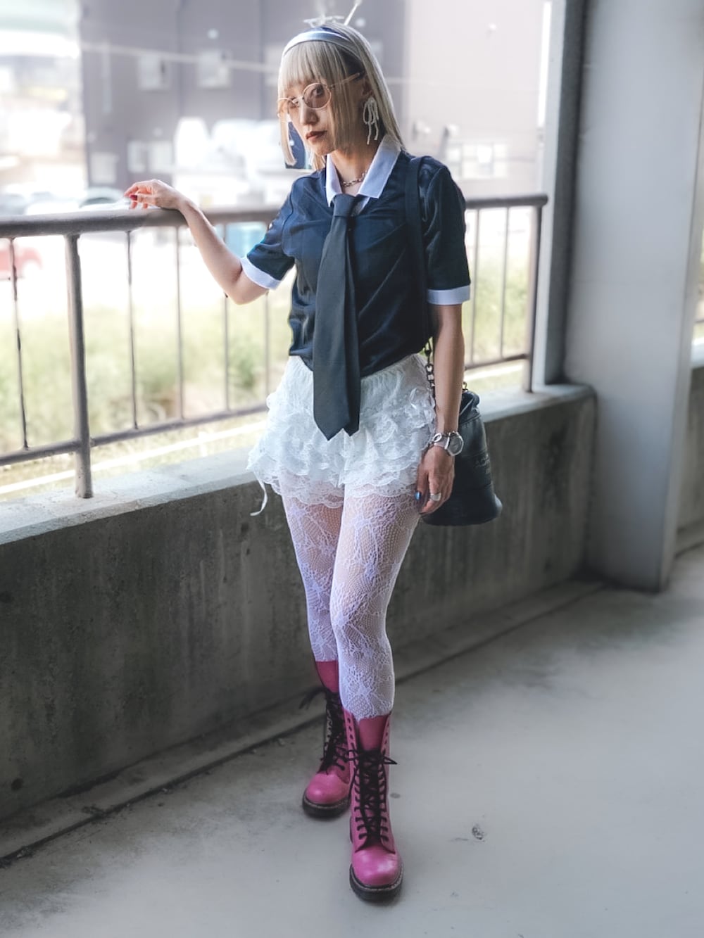 ブラック系のトップス、ピンク系のブーツ、ブラック系のショルダーバッグを着用したレディースの夏コーディネートの2枚目の写真