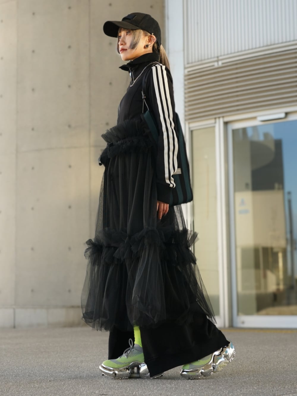 ブラック系のライダースジャケット、グリーン系のショルダーバッグ、シルバー系のスニーカーを着用したレディースの春コーディネートの3枚目の写真