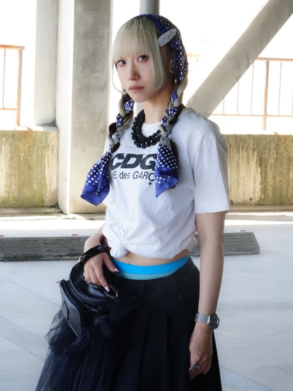 ブラック系のスカート、ブルー系のスニーカー、ホワイト系のTシャツ/カットソーを着用したレディースの春コーディネートの2枚目の写真