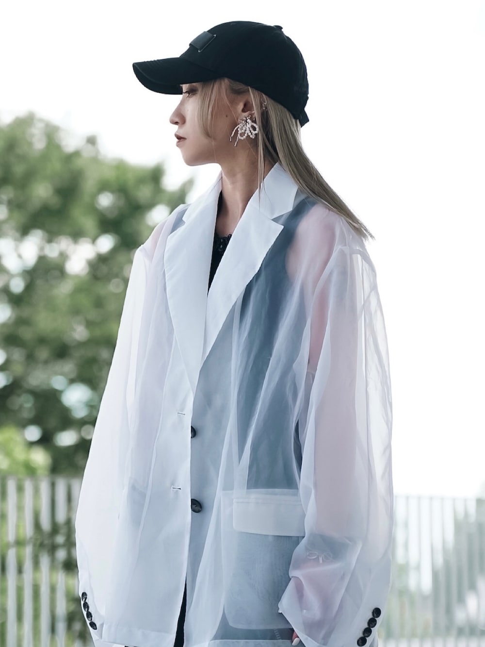 ホワイト系のテーラードジャケット、グリーン系のショルダーバッグ、ブラック系のスカートを着用したレディースの秋コーディネートの2枚目の写真