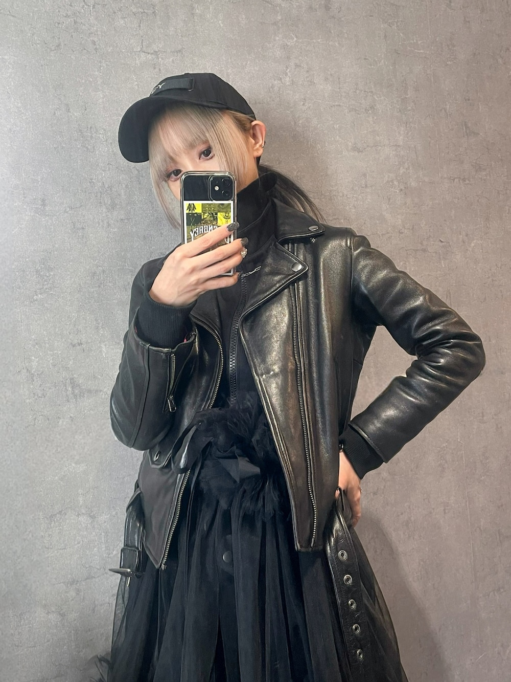 ブラック系のライダースジャケット、グリーン系のショルダーバッグ、シルバー系のスニーカーを着用したレディースの春コーディネートの4枚目の写真