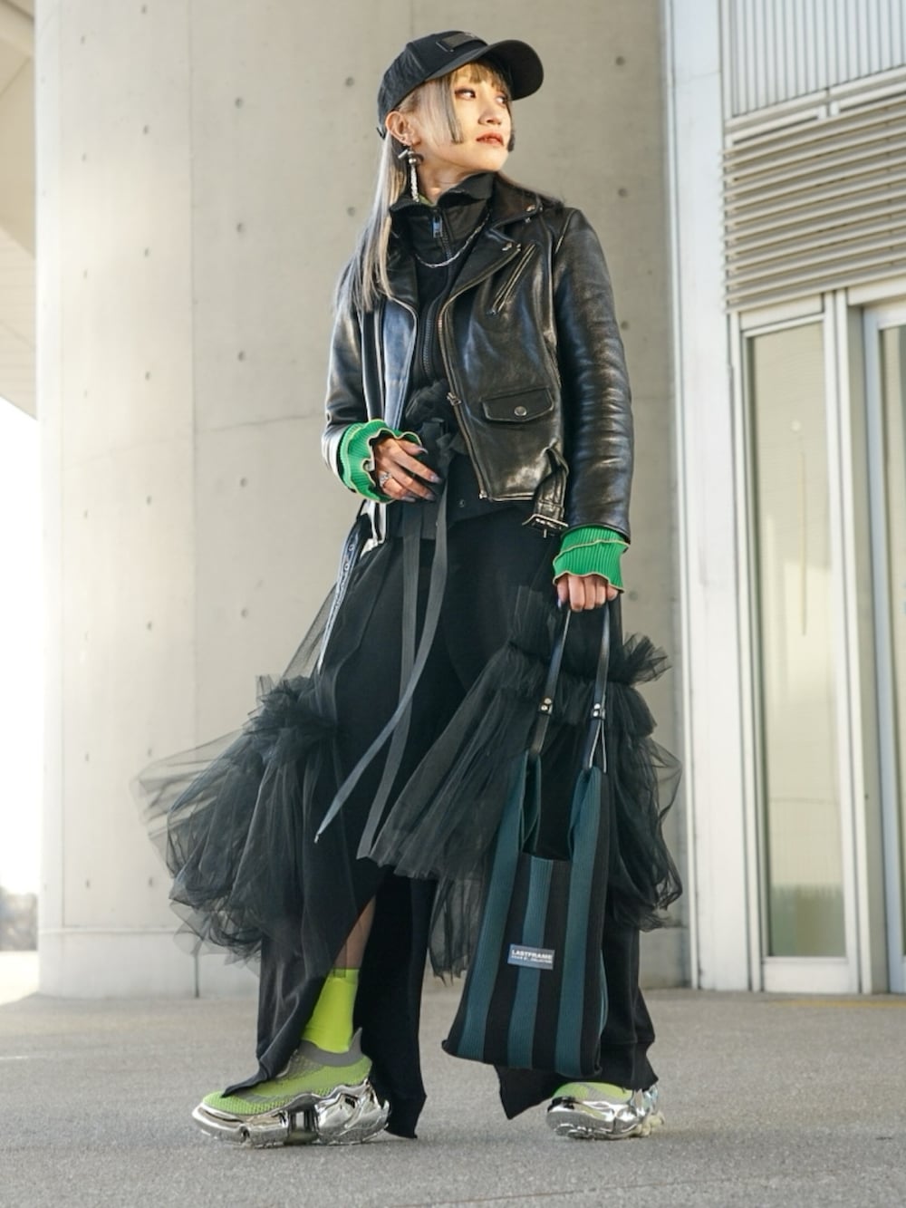 ブラック系のライダースジャケット、グリーン系のショルダーバッグ、シルバー系のスニーカーを着用したレディースの春コーディネートの2枚目の写真