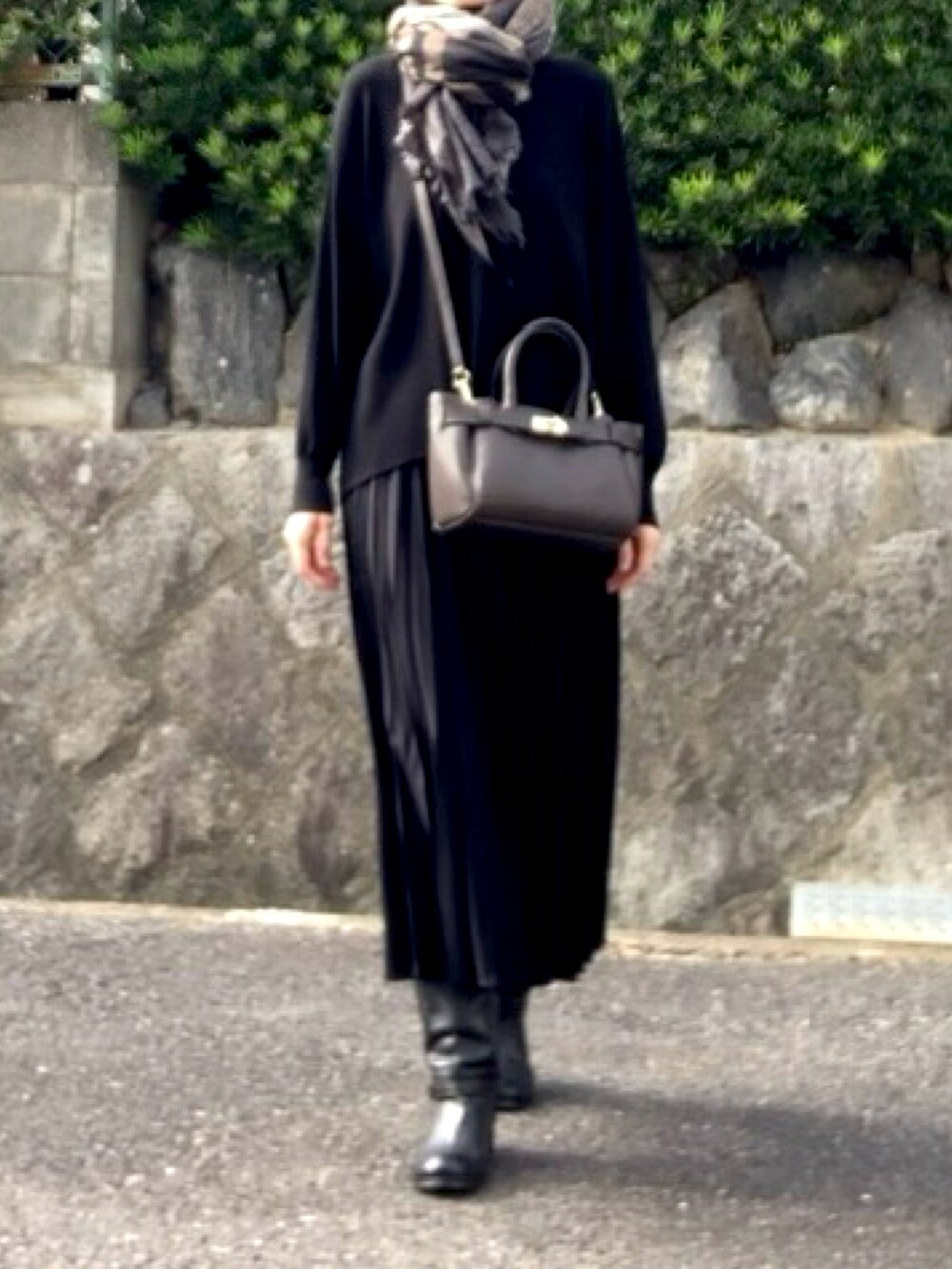 ブラウン系のハンドバッグ、ブラック系のトップス、ブラック系のスカートを着用したレディースの秋コーディネートの4枚目の写真