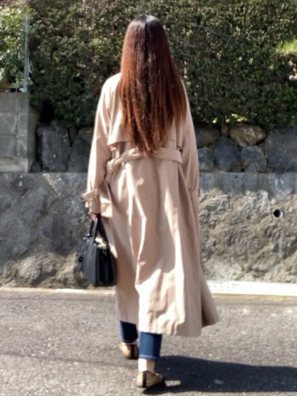 ベージュ系のトレンチコート、ブラック系のハンドバッグ、ブラック系のワンピースを着用したレディースの春コーディネートの3枚目の写真