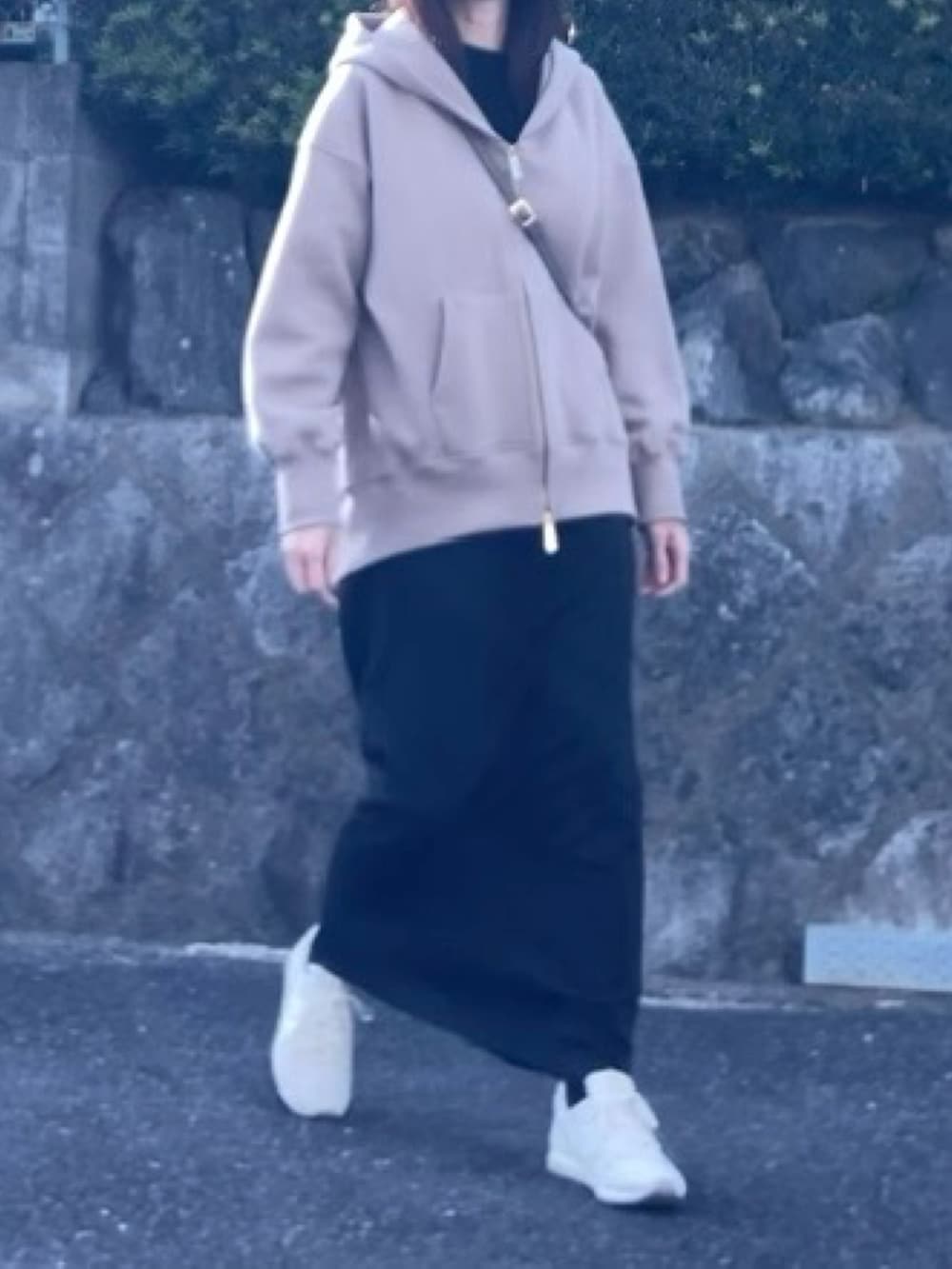 ベージュ系のパーカー、ブラック系のスカート、ベージュ系のハンドバッグを着用したレディースの冬コーディネートの2枚目の写真