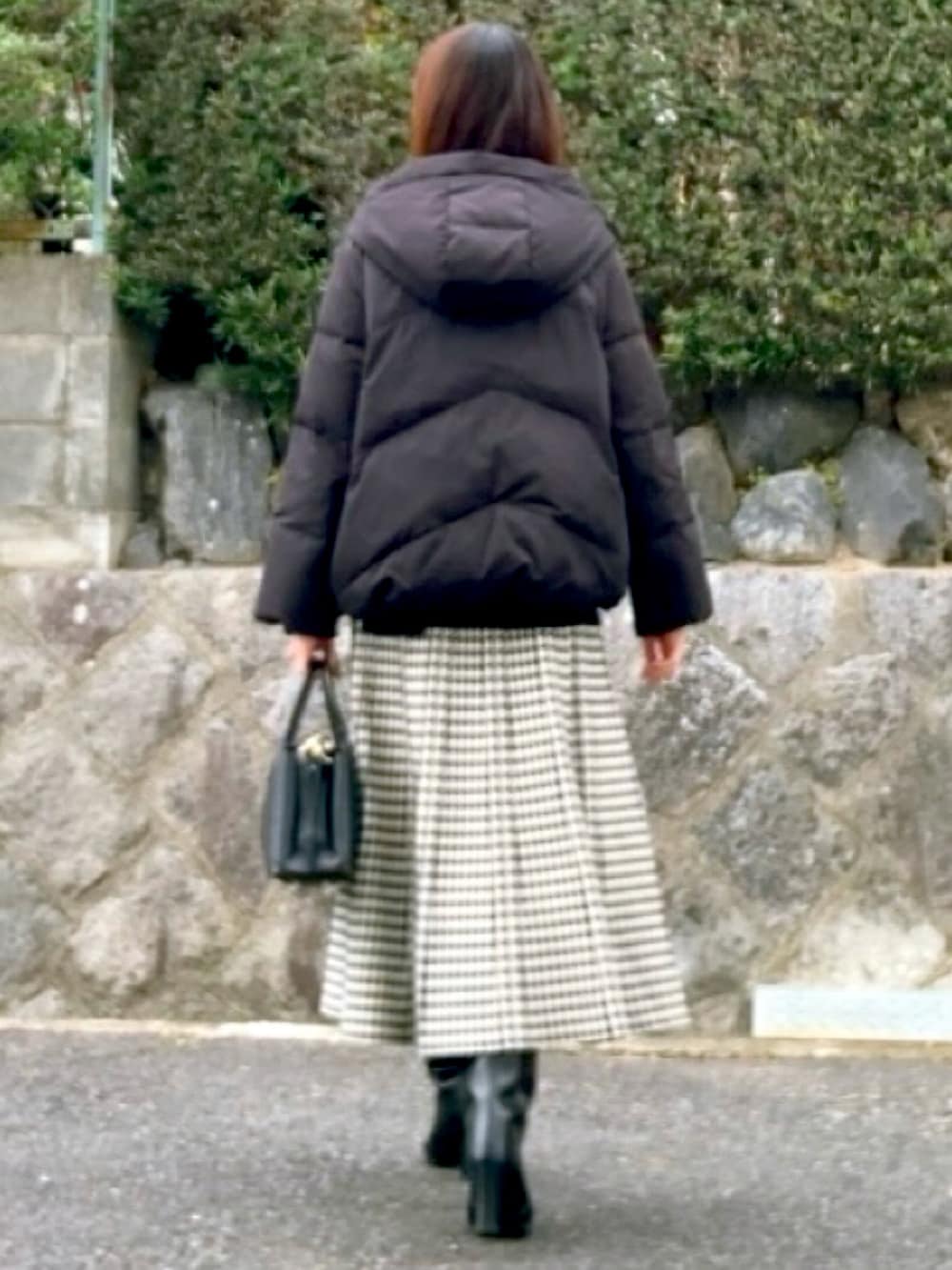 ホワイト系のスカート、ブラック系のハンドバッグを着用したレディースの冬コーディネートの2枚目の写真