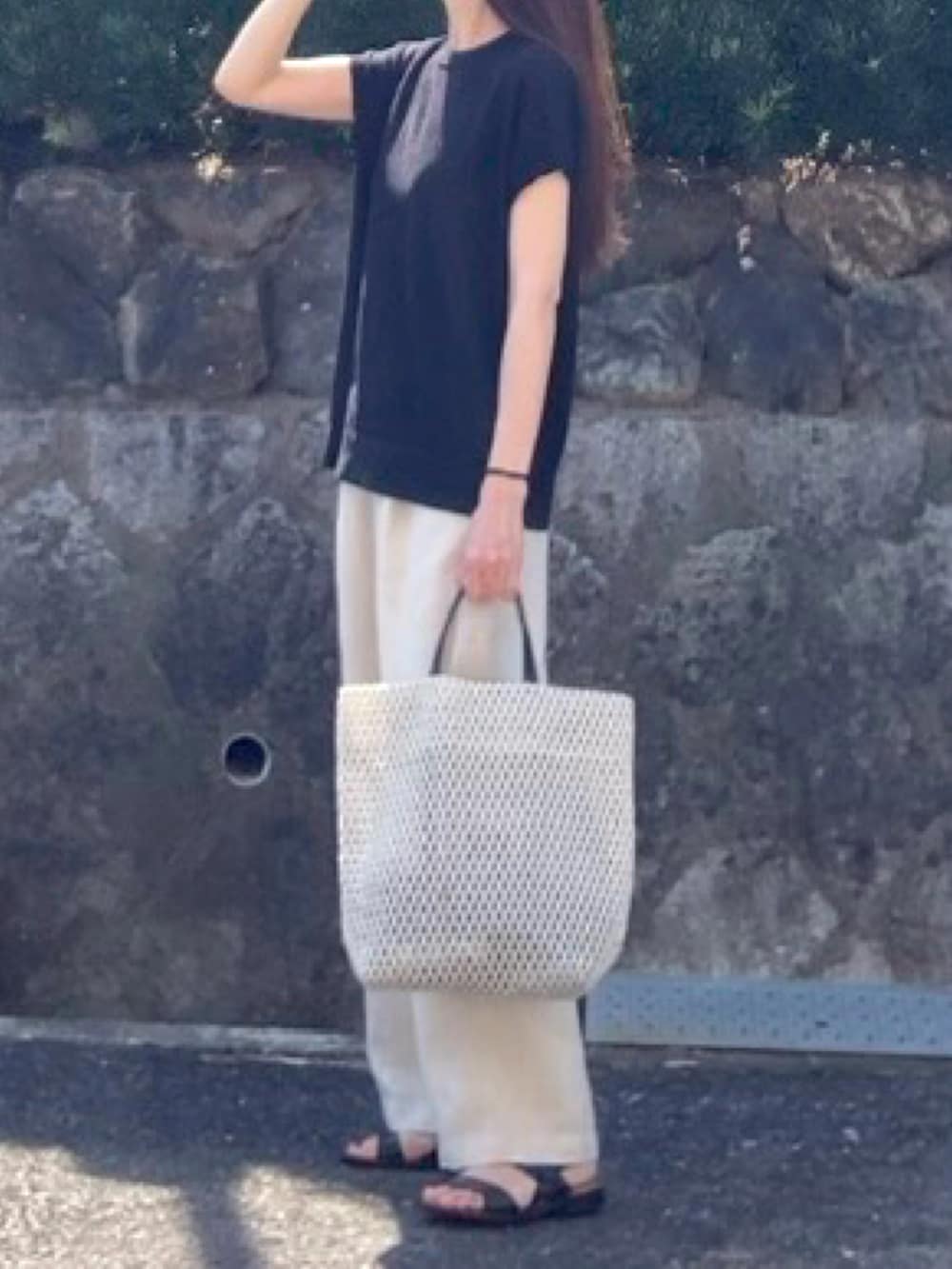 ブラック系のニット/セーター、ベージュ系のその他パンツ、ホワイト系のトートバッグを着用したレディースの夏コーディネートの2枚目の写真