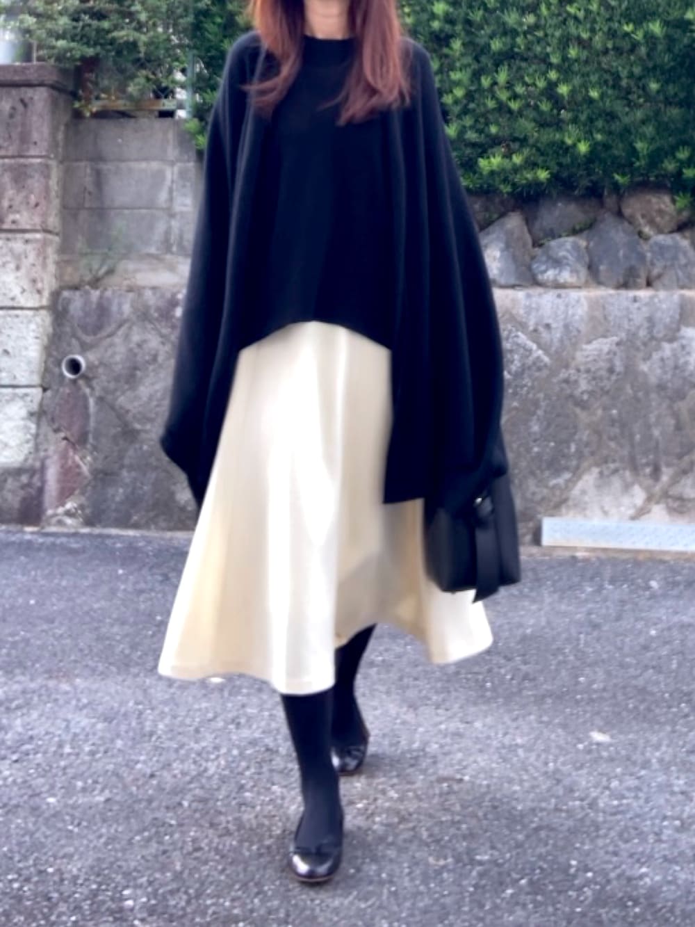 ブラック系のバッグ、ブラック系のトップス、ホワイト系のスカートを着用したレディースの秋コーディネートの2枚目の写真