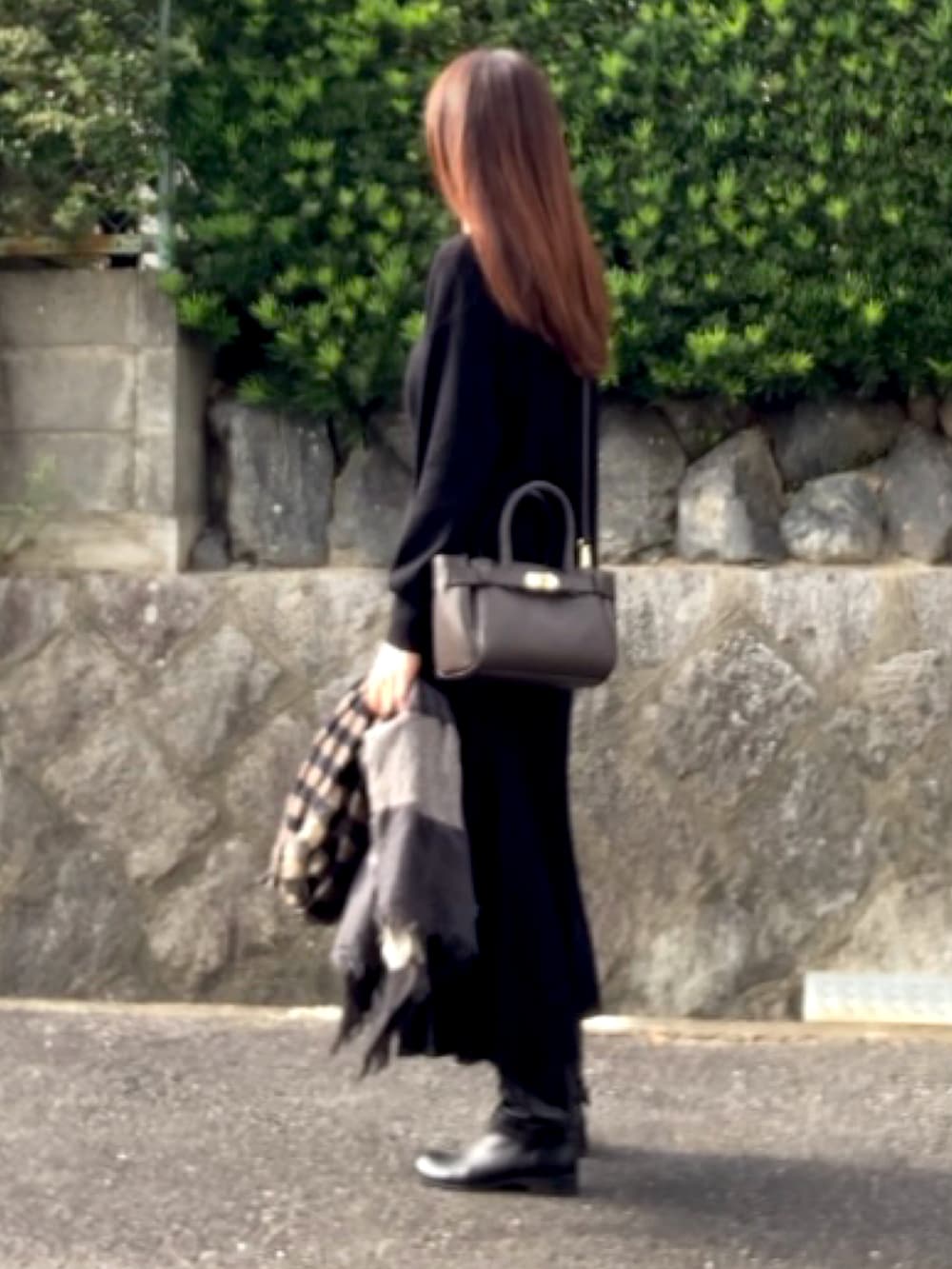 ブラウン系のハンドバッグ、ブラック系のトップス、ブラック系のスカートを着用したレディースの秋コーディネートの3枚目の写真