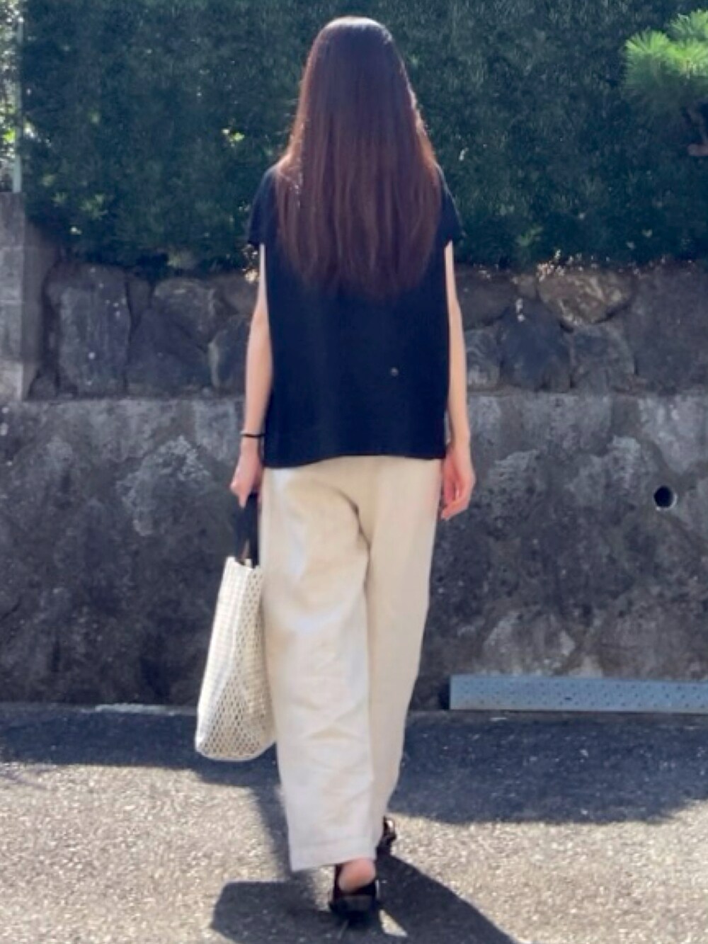 ブラック系のニット/セーター、ベージュ系のその他パンツ、ホワイト系のトートバッグを着用したレディースの夏コーディネートの4枚目の写真