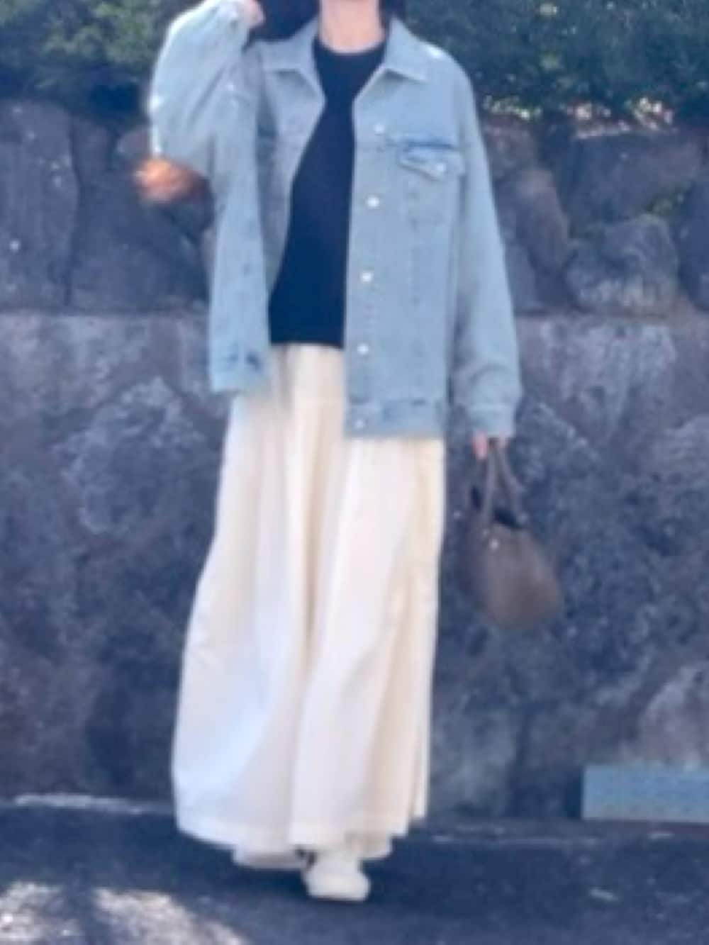 ブルー系のデニムジャケット、ベージュ系のハンドバッグ、ブラック系のニット/セーターを着用したレディースの春コーディネートの3枚目の写真