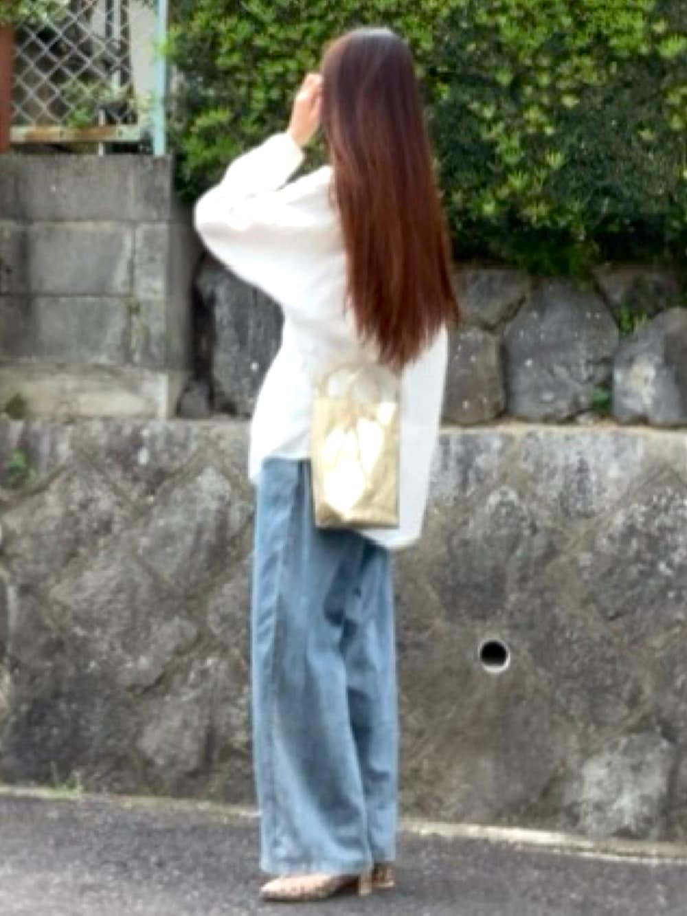 ブルー系のデニムパンツ、ホワイト系のシャツ/ブラウス、ゴールド系のトートバッグを着用したレディースの春コーディネートの2枚目の写真