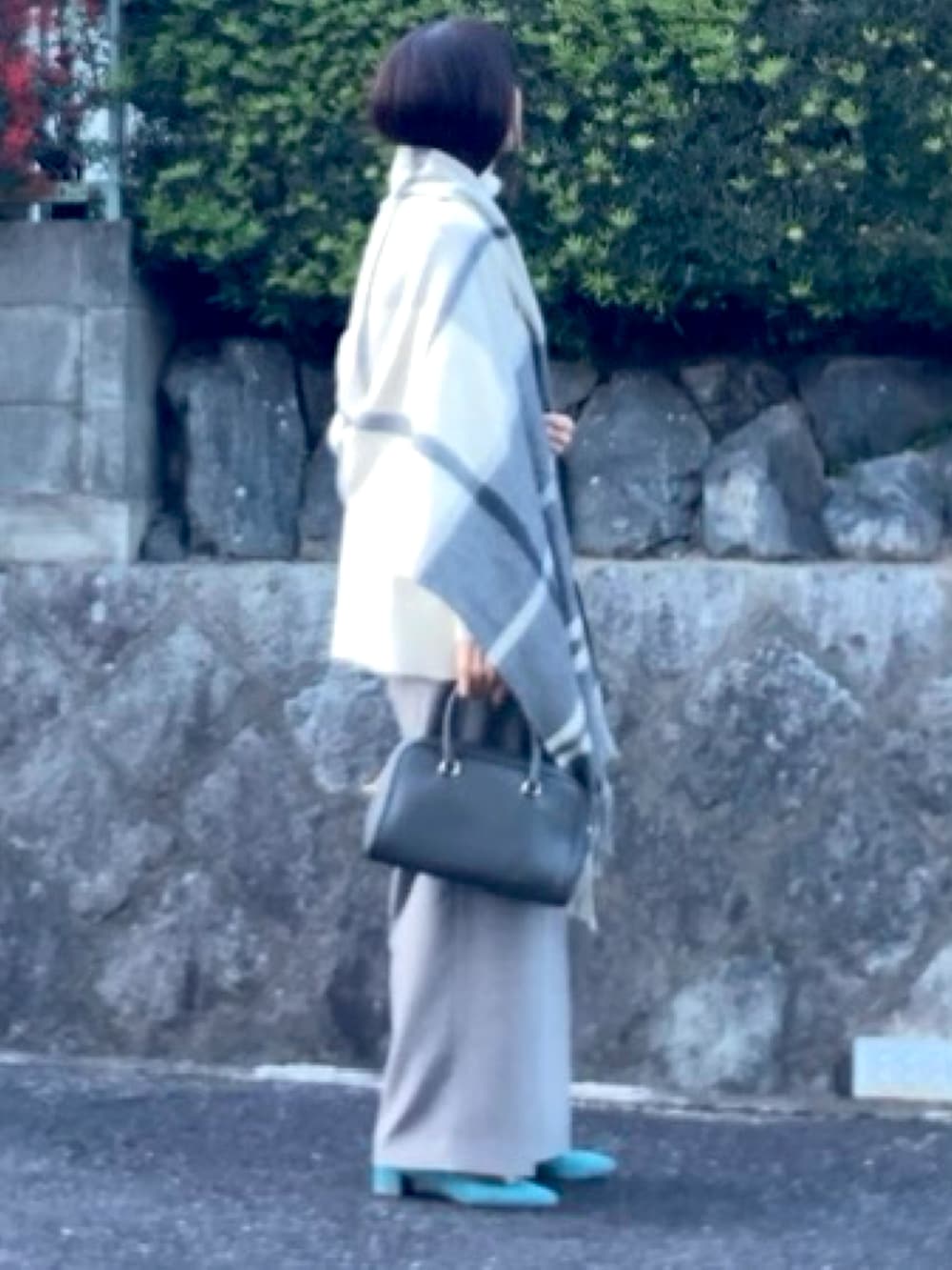 グレー系のボストンバッグ、ホワイト系のアンサンブル、ブルー系のパンプスを着用したレディースの冬コーディネートの2枚目の写真