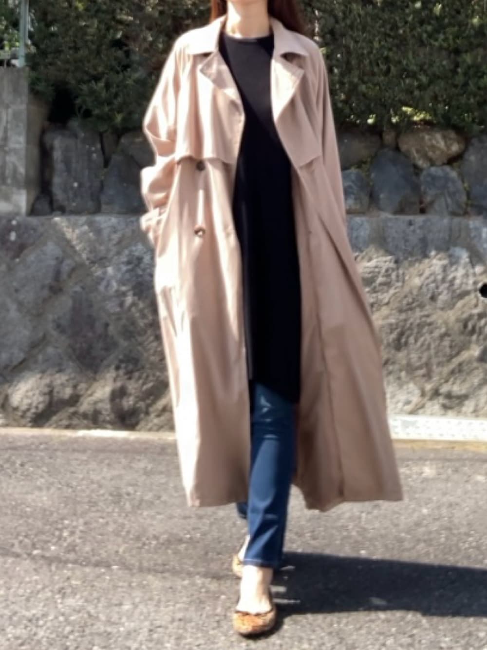 ベージュ系のトレンチコート、ブラック系のハンドバッグ、ブラック系のワンピースを着用したレディースの春コーディネートの2枚目の写真