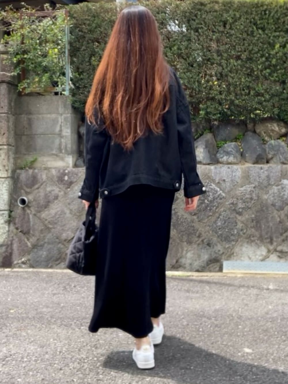 ブラック系のデニムジャケット、ブラック系のスカート、ブラック系のバッグを着用したレディースの春コーディネートの3枚目の写真