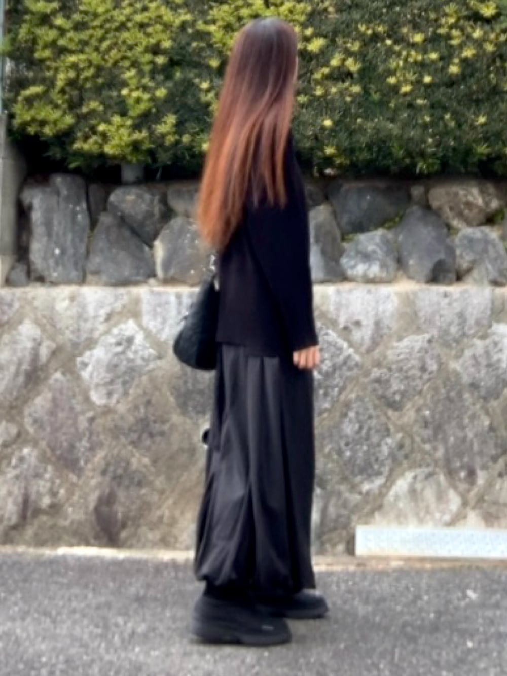 ブラック系のバッグ、ブラック系のニット/セーター、ブラック系のスカートを着用したレディースの冬コーディネートの3枚目の写真