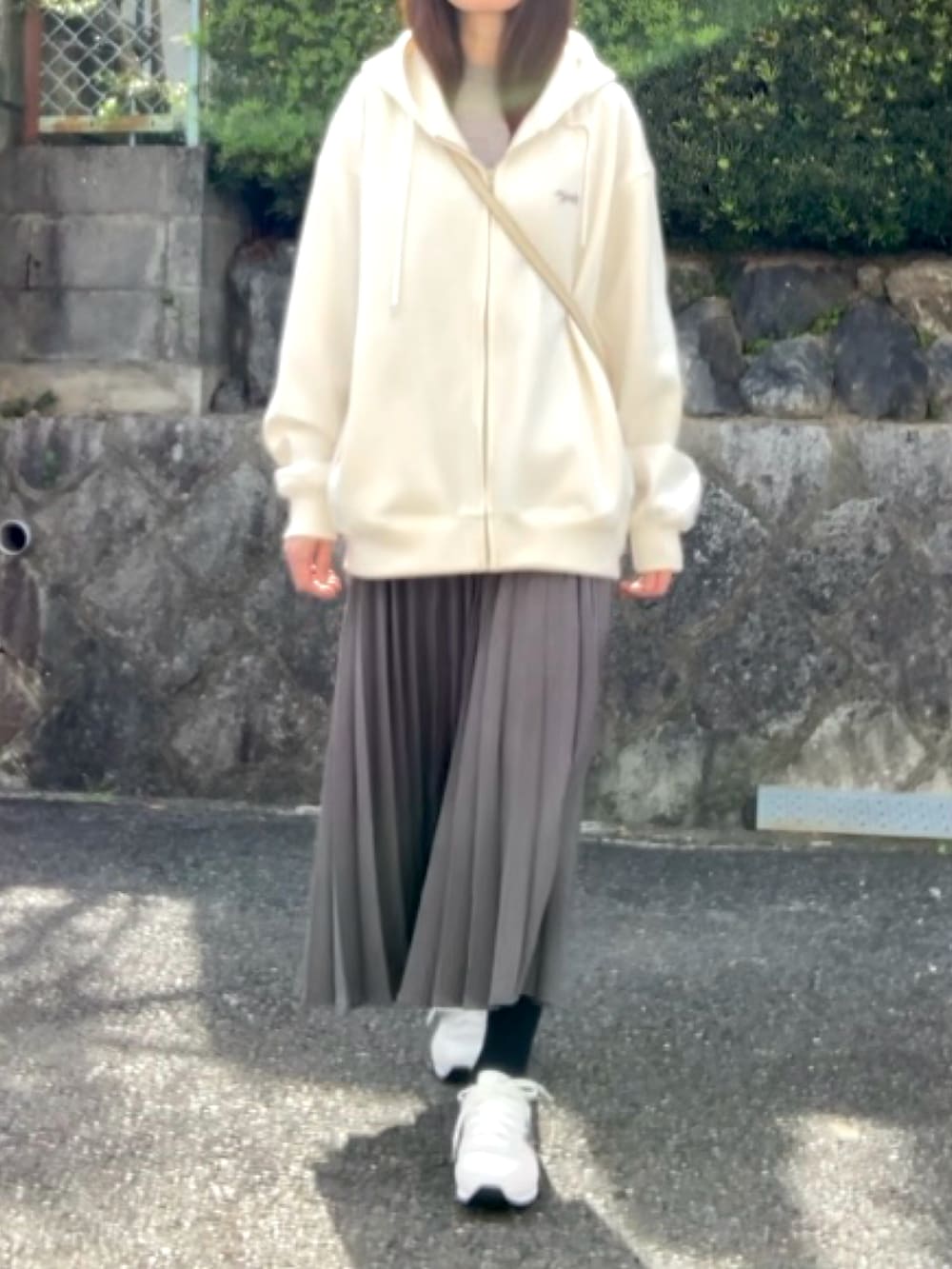 ホワイト系のパーカー、グレー系のスカート、ホワイト系のスニーカーを着用したレディースの春コーディネートの3枚目の写真