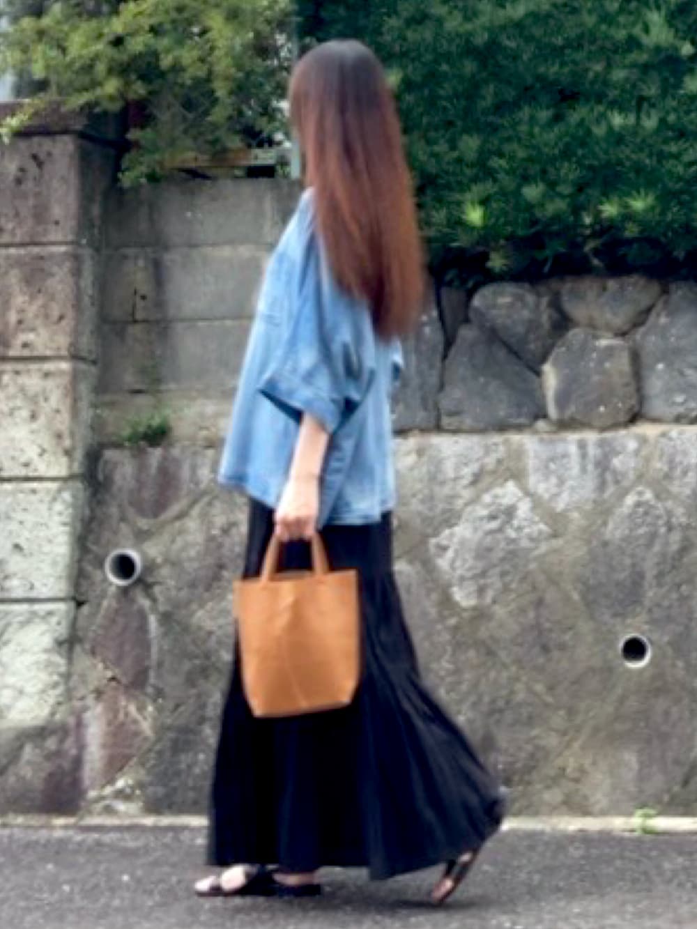 ブラック系のスカート、イエロー系のトートバッグ、ブラック系のサンダルを着用したレディースの夏コーディネートの2枚目の写真