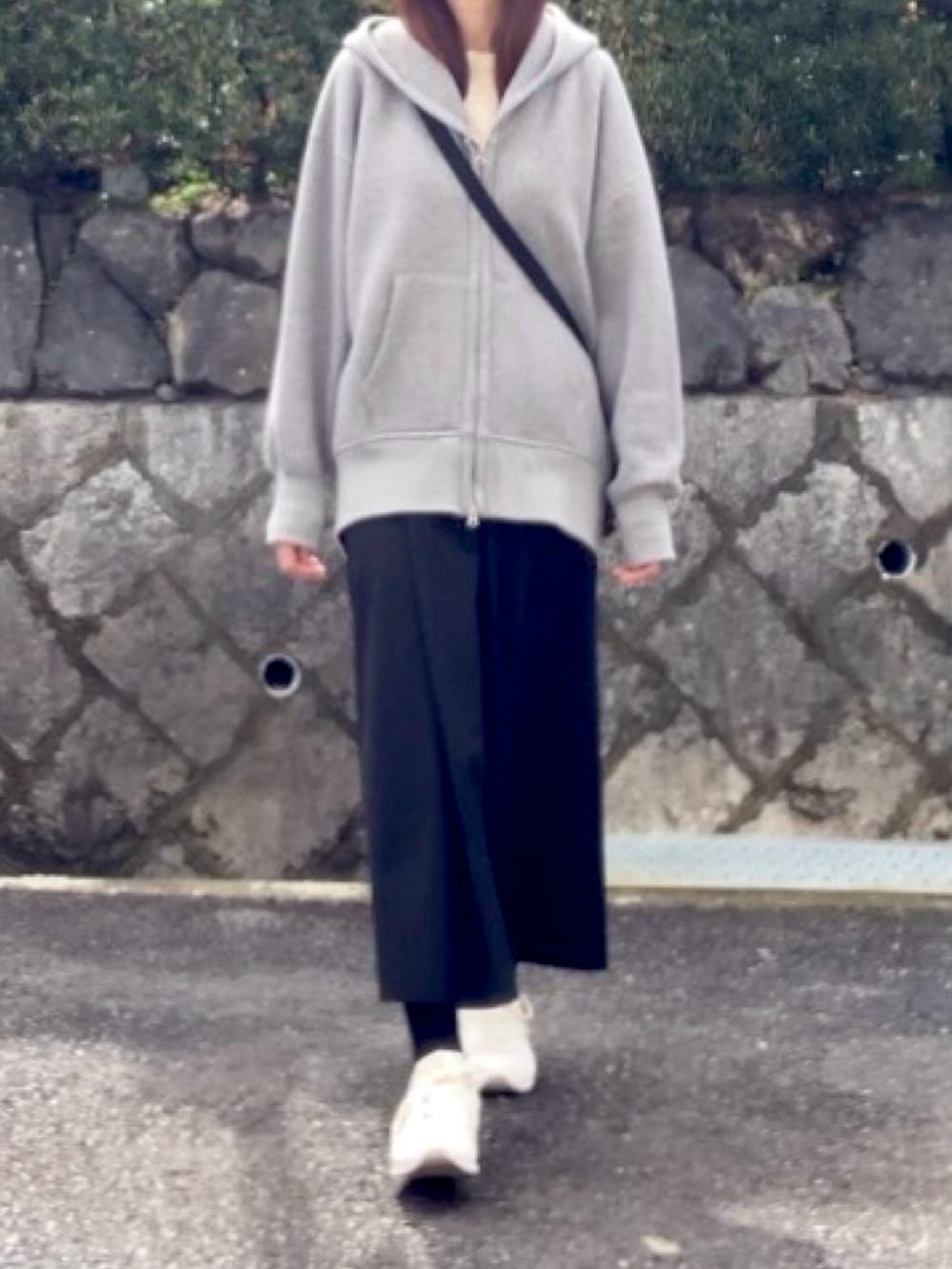 ブラック系のスカート、ホワイト系のスニーカー、グレー系のパーカーを着用したレディースの春コーディネートの4枚目の写真