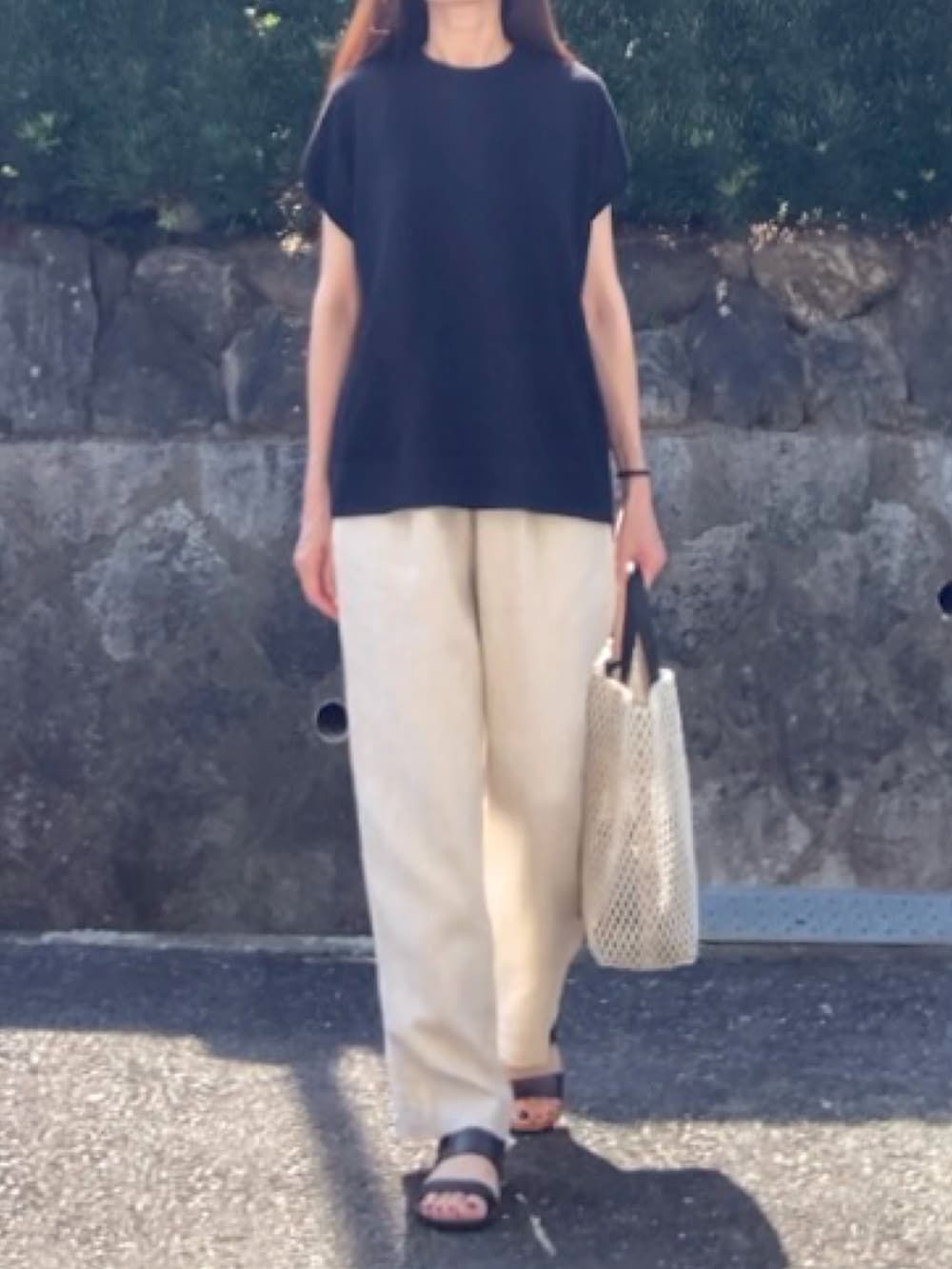 ブラック系のニット/セーター、ベージュ系のその他パンツ、ホワイト系のトートバッグを着用したレディースの夏コーディネートの3枚目の写真