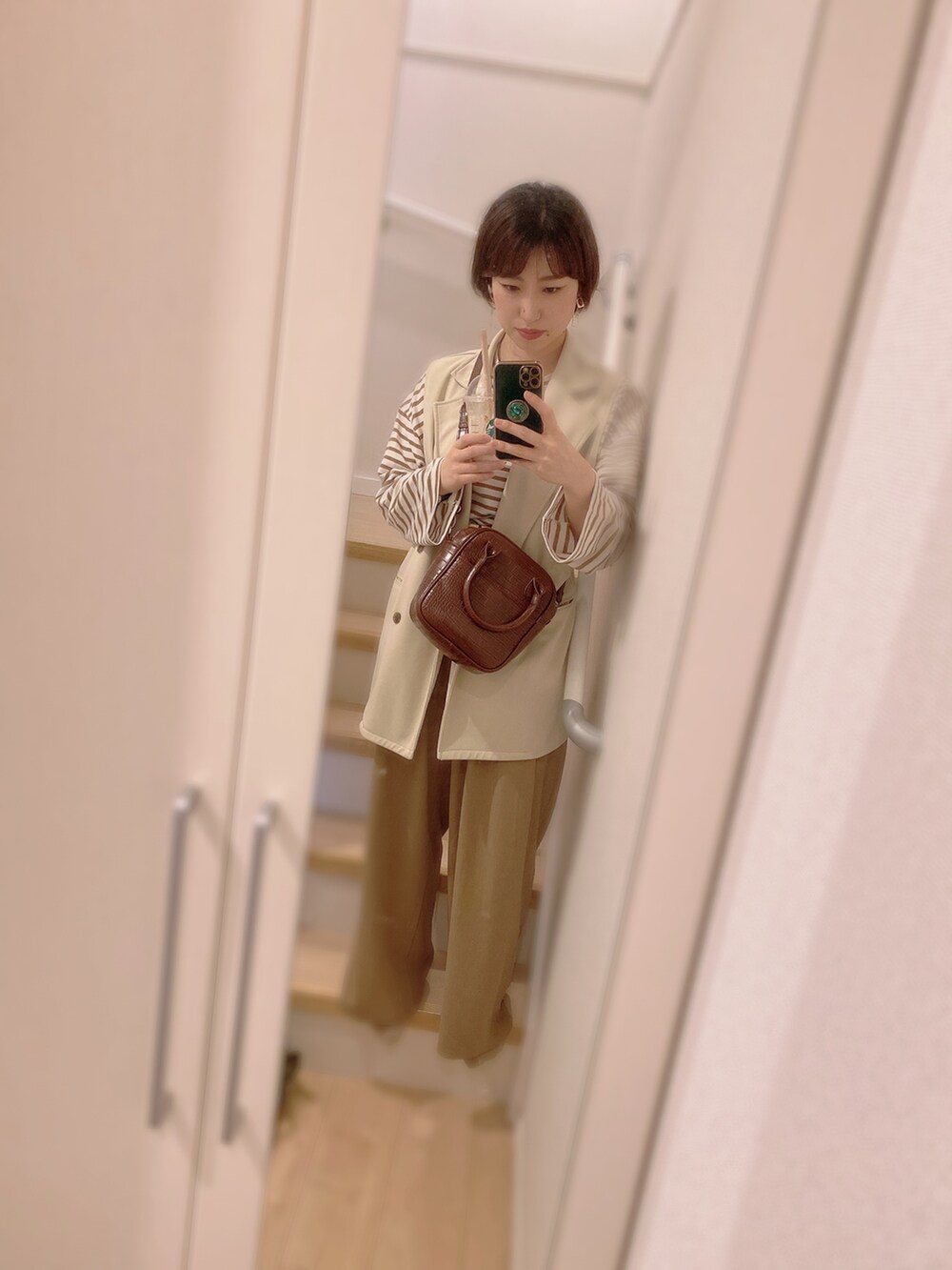 レッド系のトップス、ブラウン系のTシャツ/カットソー、ブラウン系のハンドバッグを着用したレディースの秋コーディネートの2枚目の写真