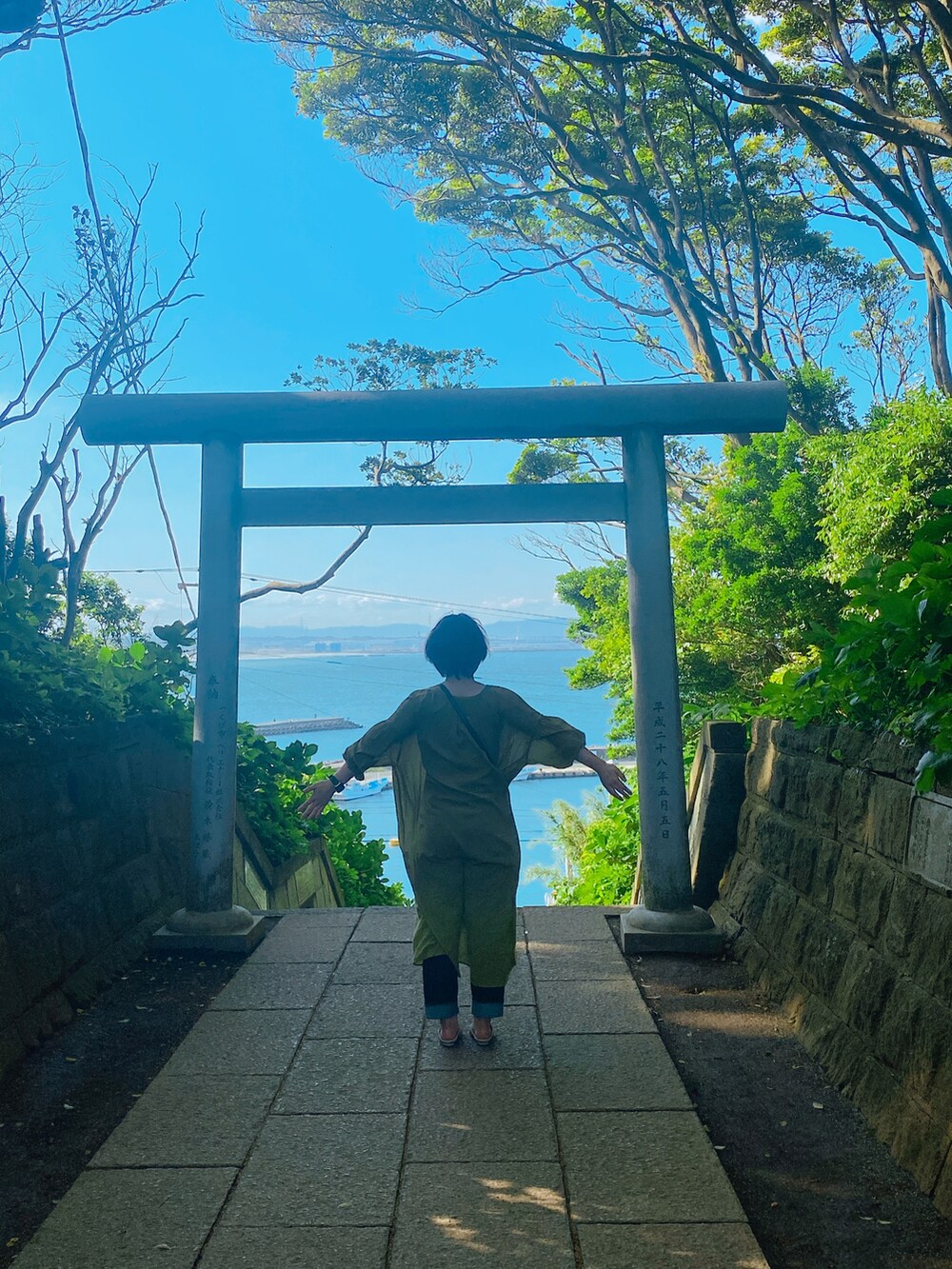 イエロー系のワンピース、ホワイト系のその他シューズ、ブラウン系のハンドバッグを着用したレディースの春コーディネートの2枚目の写真