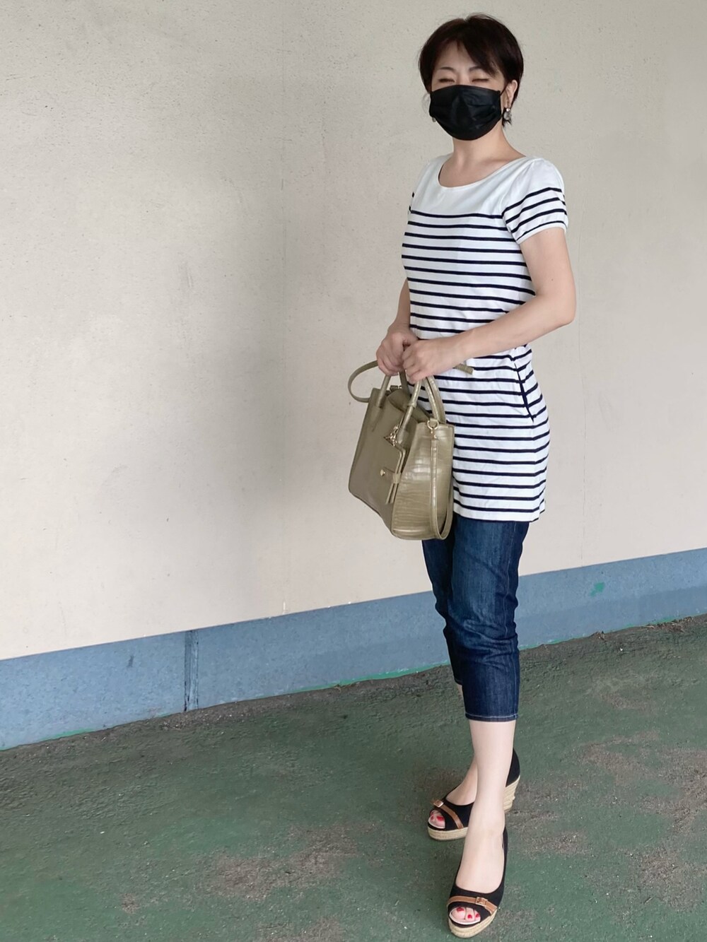 ホワイト系のトップス、グリーン系のショルダーバッグ、ブルー系のデニムパンツを着用したレディースの夏コーディネートの2枚目の写真