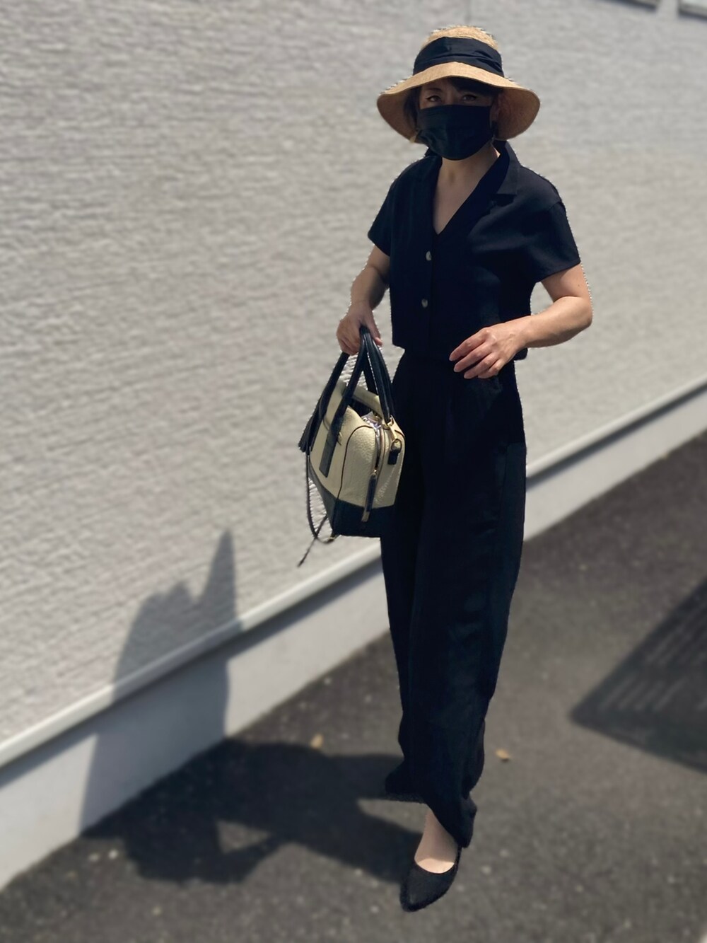 ブラック系のトップス、ブラック系のパンツ、ブラック系のバッグを着用したレディースの夏コーディネートの2枚目の写真