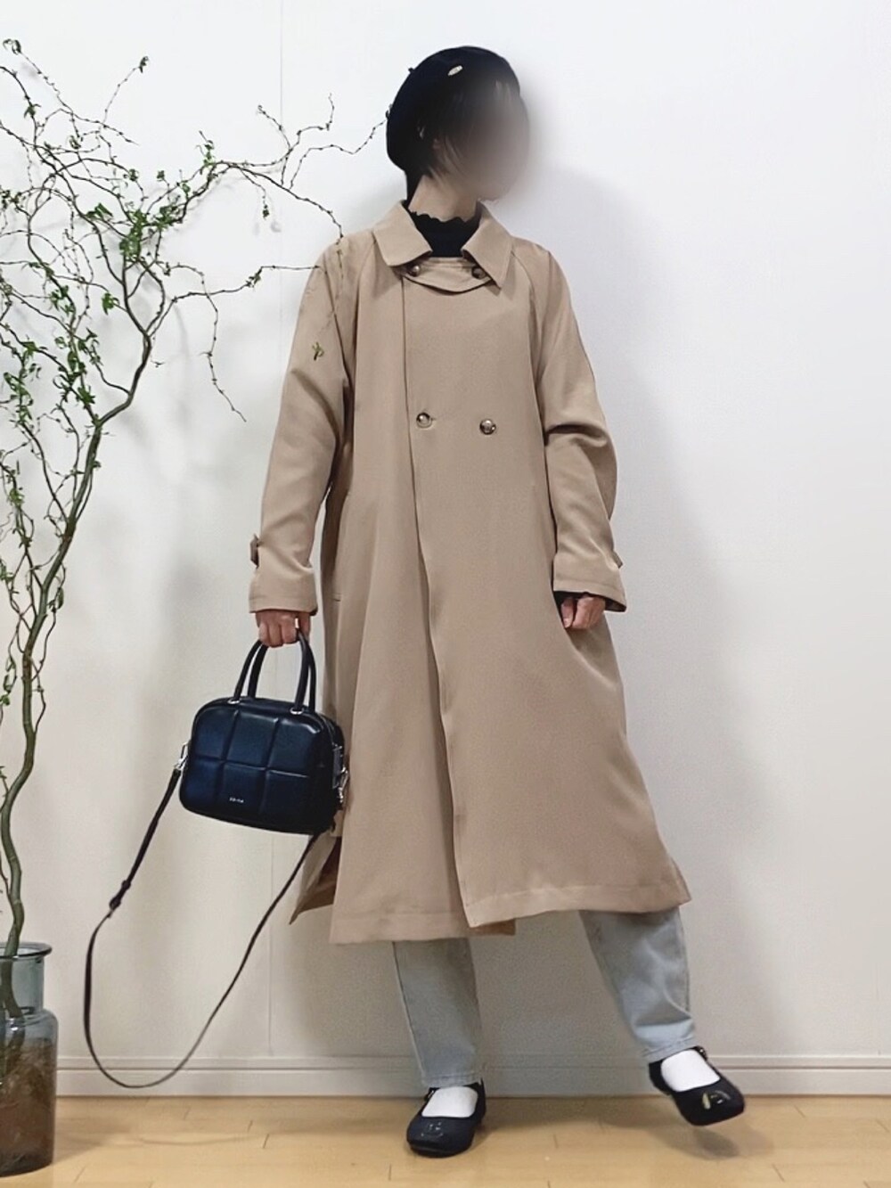 ベージュ系のトレンチコート、ブラック系のTシャツ/カットソー、ブルー系のデニムパンツを着用したレディースの春コーディネートの2枚目の写真