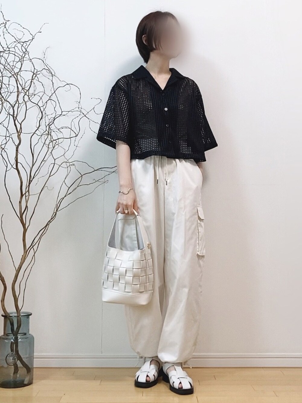 ブラック系のトップス、ホワイト系のカーゴパンツ、ホワイト系のショルダーバッグを着用したレディースの夏コーディネートの2枚目の写真