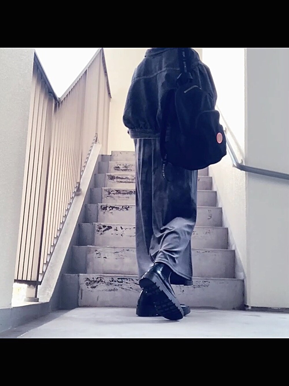 ブラック系のデニムジャケット、グレー系のワンピース/ドレス、ブラック系のバックパック/リュックを着用したレディースの秋コーディネートの3枚目の写真