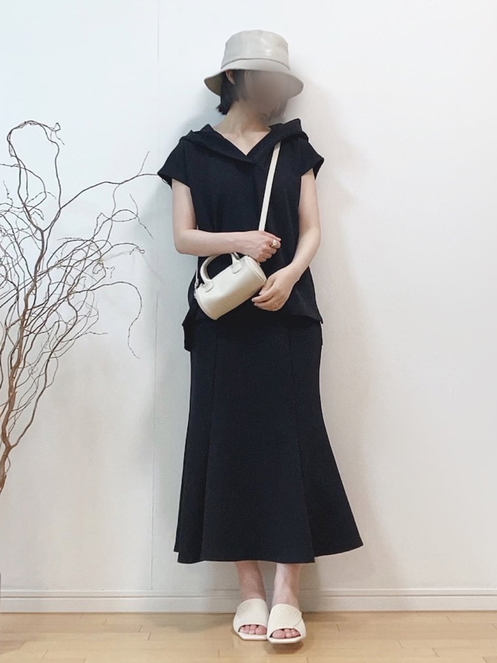 ブラック系のパーカー、ブラック系のスカート、ホワイト系のサンダルを着用したレディースの夏コーディネートの2枚目の写真