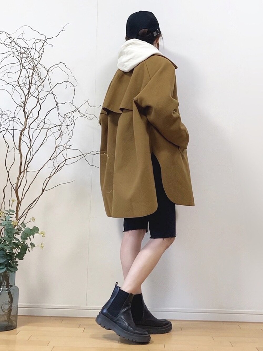 イエロー系のピーコート、ブラック系のデニムパンツ、ブラック系のキャップを着用したレディースの冬コーディネートの3枚目の写真