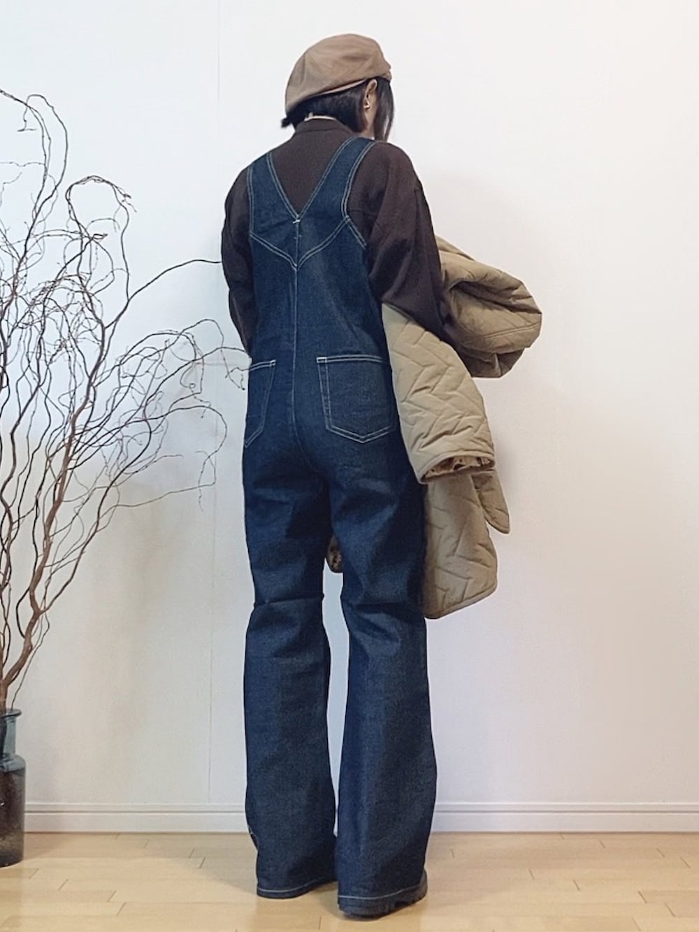 ブルー系のサロペット/オーバーオール、ベージュ系のダウンジャケット/コート、ブラック系のブーツを着用したレディースの冬コーディネートの2枚目の写真