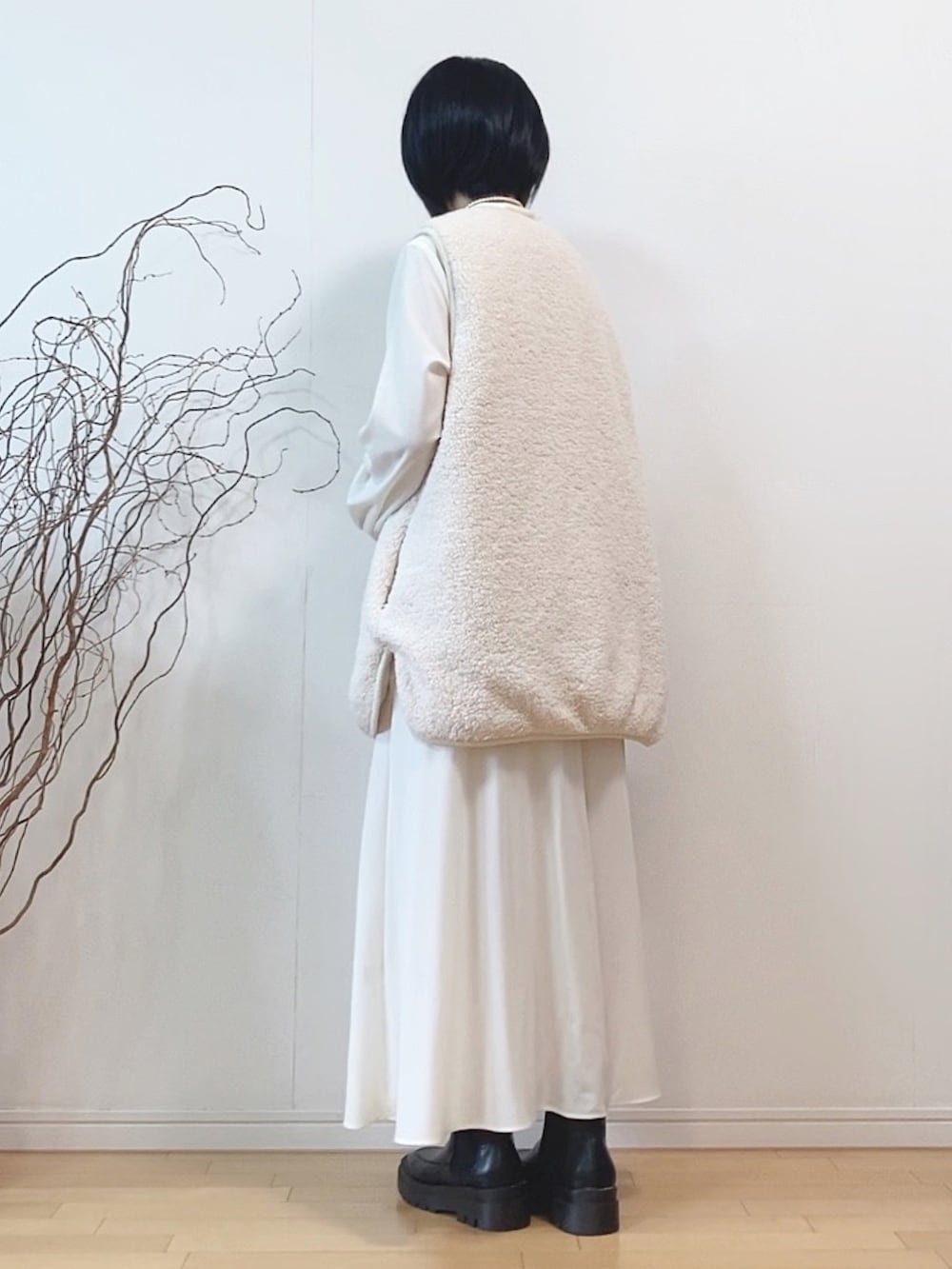 ホワイト系のベスト、グレー系のワンピース、ブラック系のブーツを着用したレディースの秋コーディネートの3枚目の写真