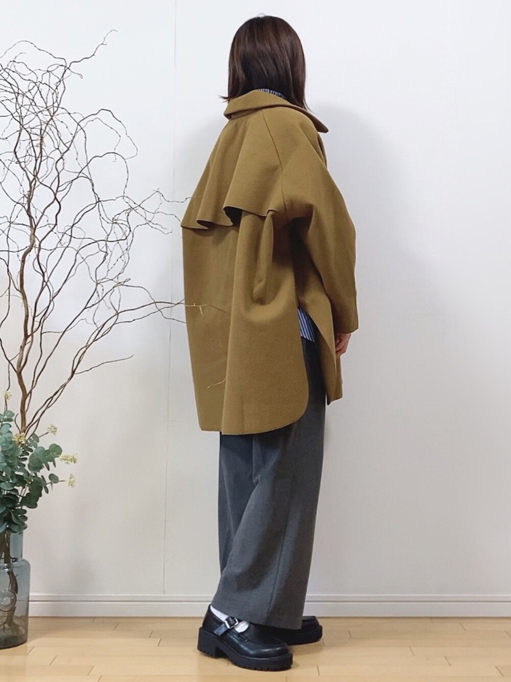 イエロー系のピーコート、ブルー系のトップス、グレー系のパンツを着用したレディースの春コーディネートの2枚目の写真