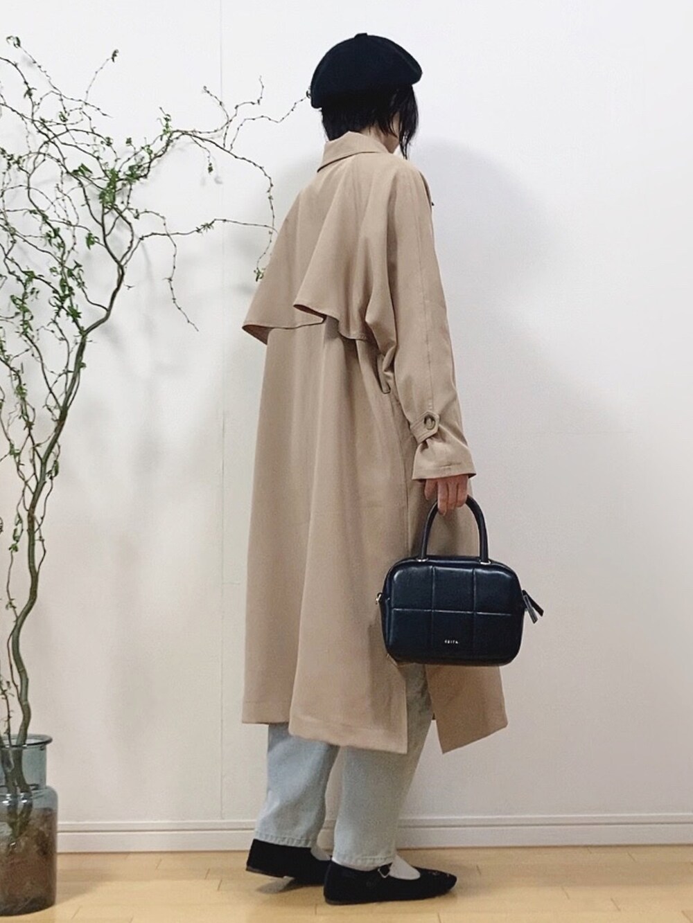 ベージュ系のトレンチコート、ブラック系のTシャツ/カットソー、ブルー系のデニムパンツを着用したレディースの春コーディネートの4枚目の写真