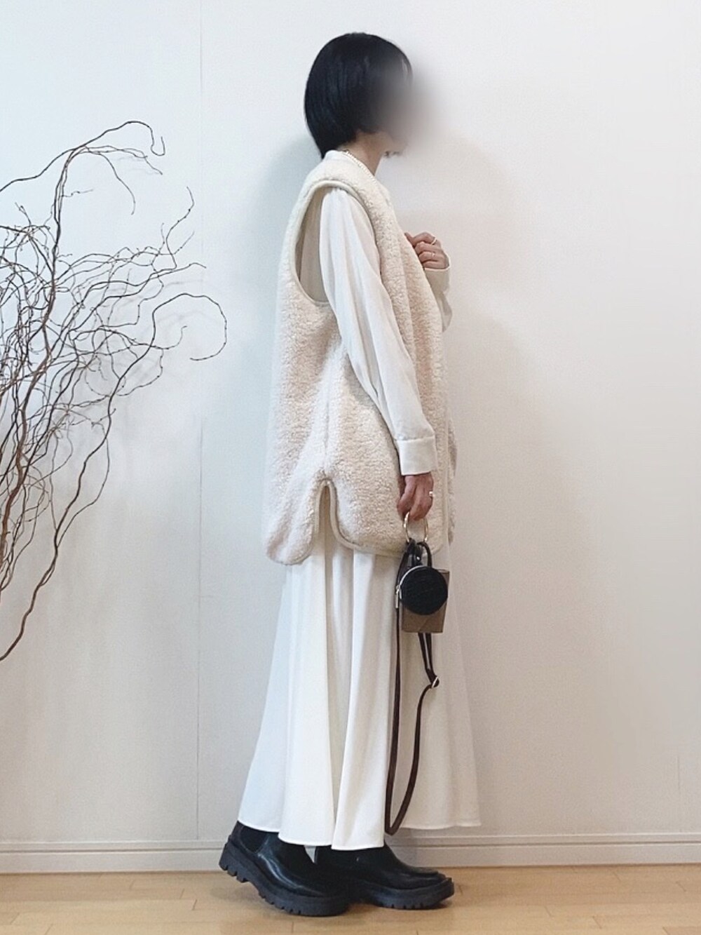 ホワイト系のベスト、グレー系のワンピース、ブラック系のブーツを着用したレディースの秋コーディネートの2枚目の写真