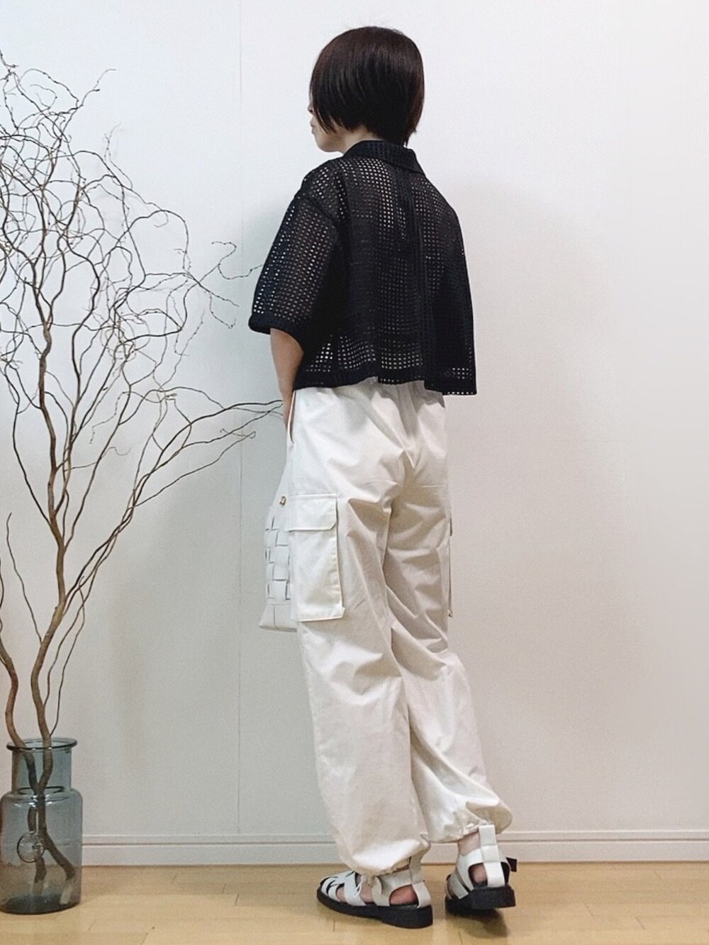 ブラック系のトップス、ホワイト系のカーゴパンツ、ホワイト系のショルダーバッグを着用したレディースの夏コーディネートの3枚目の写真