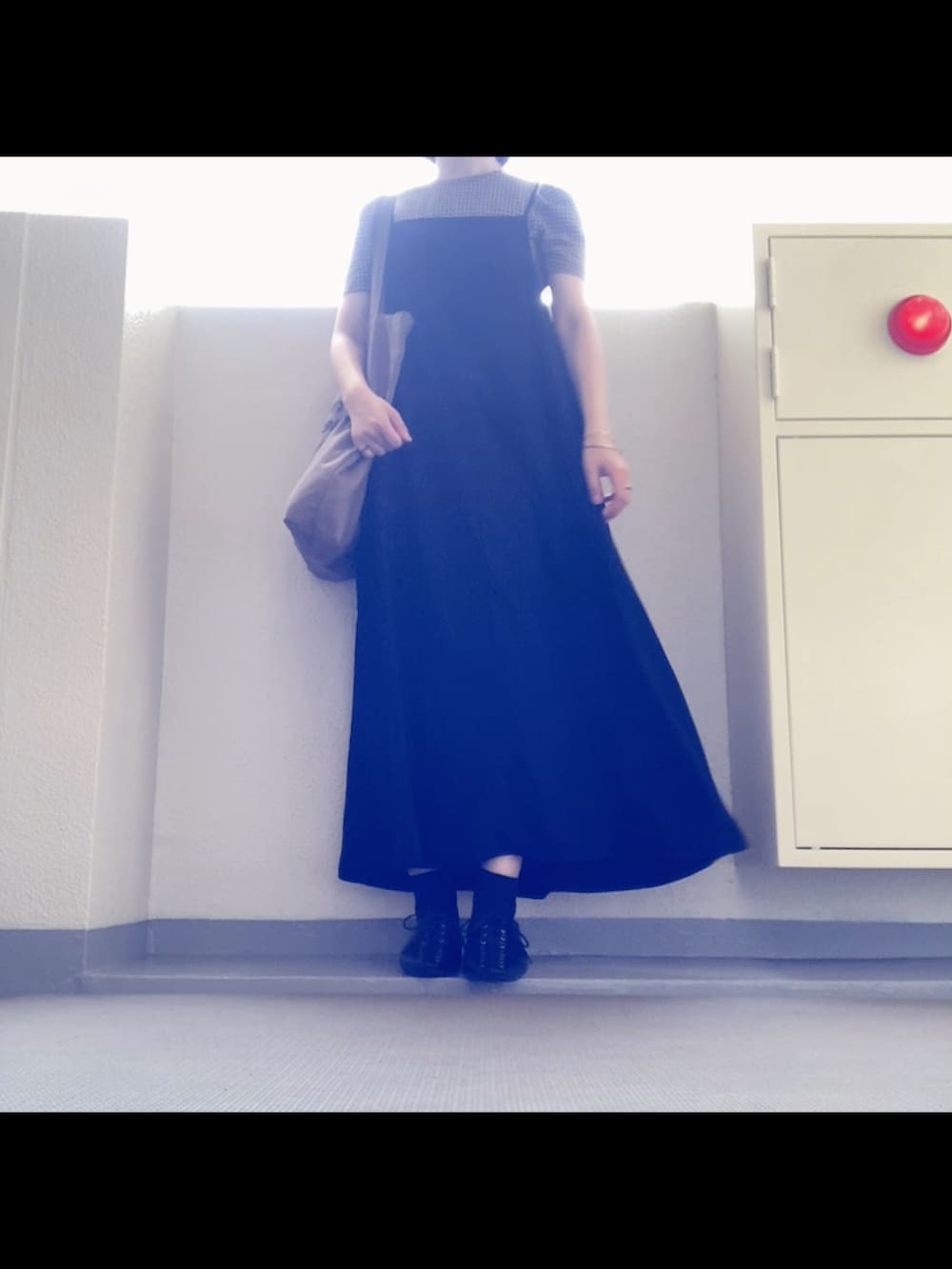 ブラック系のワンピース/ドレス、ブラウン系のトートバッグ、ブラック系のサンダルを着用したレディースの秋コーディネートの2枚目の写真