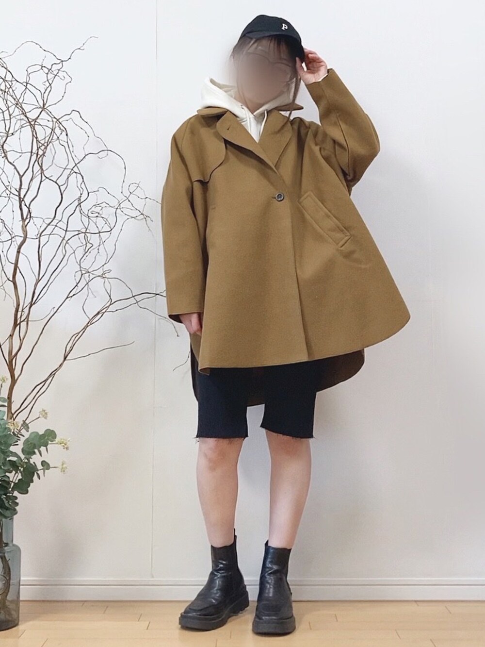 イエロー系のピーコート、ブラック系のデニムパンツ、ブラック系のキャップを着用したレディースの冬コーディネートの2枚目の写真