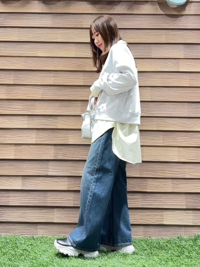 グレー系のスウェット、イエロー系のシャツ/ブラウス、ブルー系のデニムパンツを着用したレディースの春コーディネートの2枚目の写真