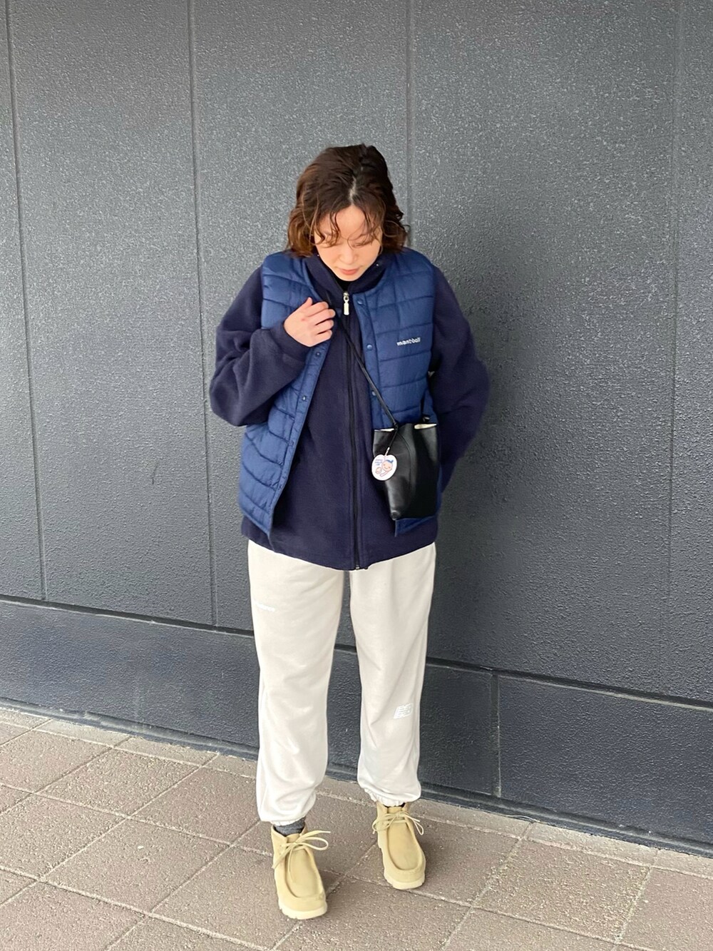 ベージュ系のブーツ、ブルー系のダウンベスト、ブラック系のショルダーバッグを着用したレディースの冬コーディネートの2枚目の写真