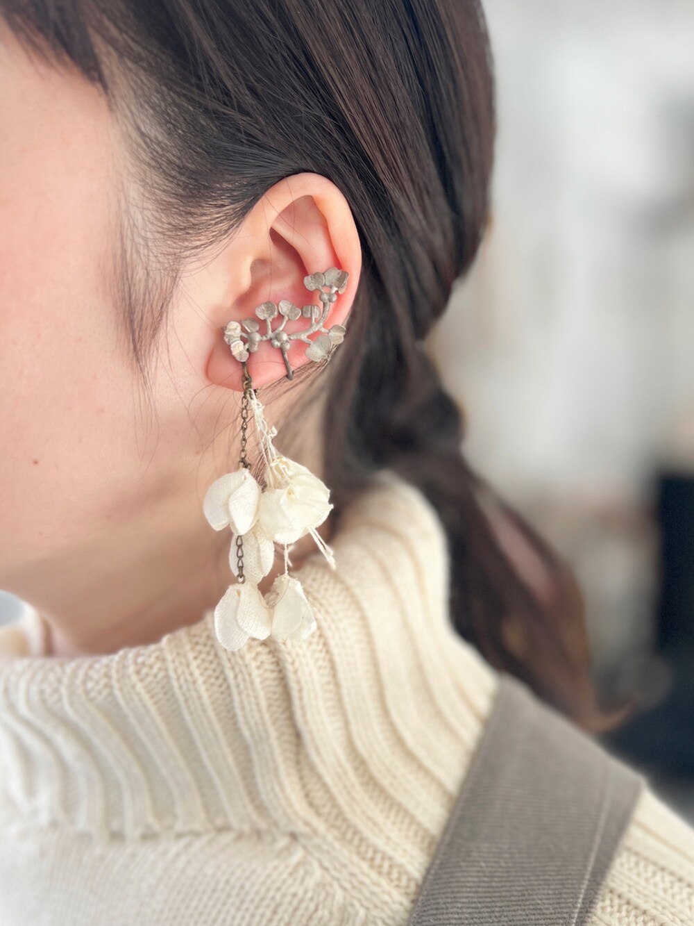 ホワイト系のトートバッグ、グレー系のジャンパースカート、ホワイト系のニット/セーターを着用したレディースの冬コーディネートの2枚目の写真